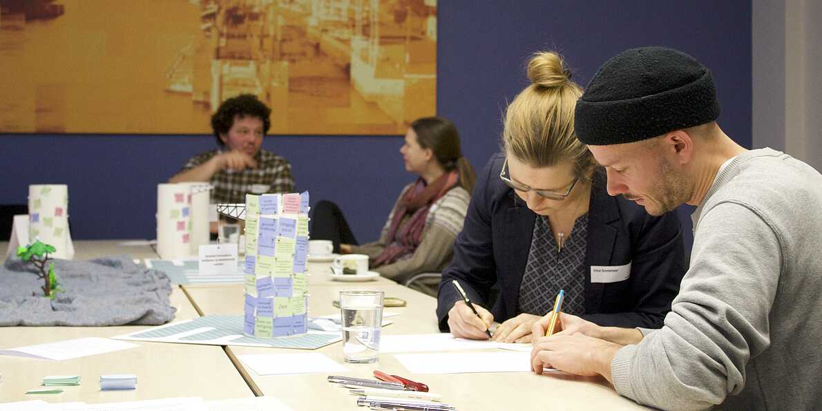 zwei personen schreiben auf ein Papier an einem Tisch